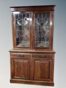 An Art Nouveau mahogany double door bookcase with leaded glass doors