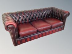 An oxblood Chesterfield three seater club settee with matching armchair