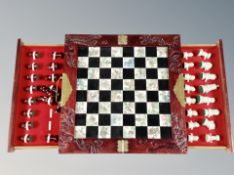 A decorative carved folding oriental chessboard with pieces