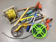 A garden hose on reel together with a strimmer, trundle wheel, sledge hammer,
