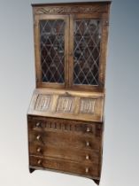 An oak linen fold bureau bookcase with leaded glass doors,