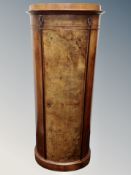 A walnut oval shaped cabinet with shelved interior,