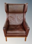 A Scandinavian brown leather wing back armchair