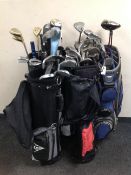 Five golf bags containing irons and drivers,