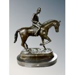 A bronze figure of a jockey on horseback, mounted on marble plinth,