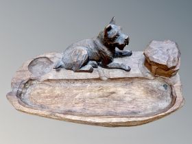 A twentieth century adzed oak desk stand, modelled with a seated terrier,