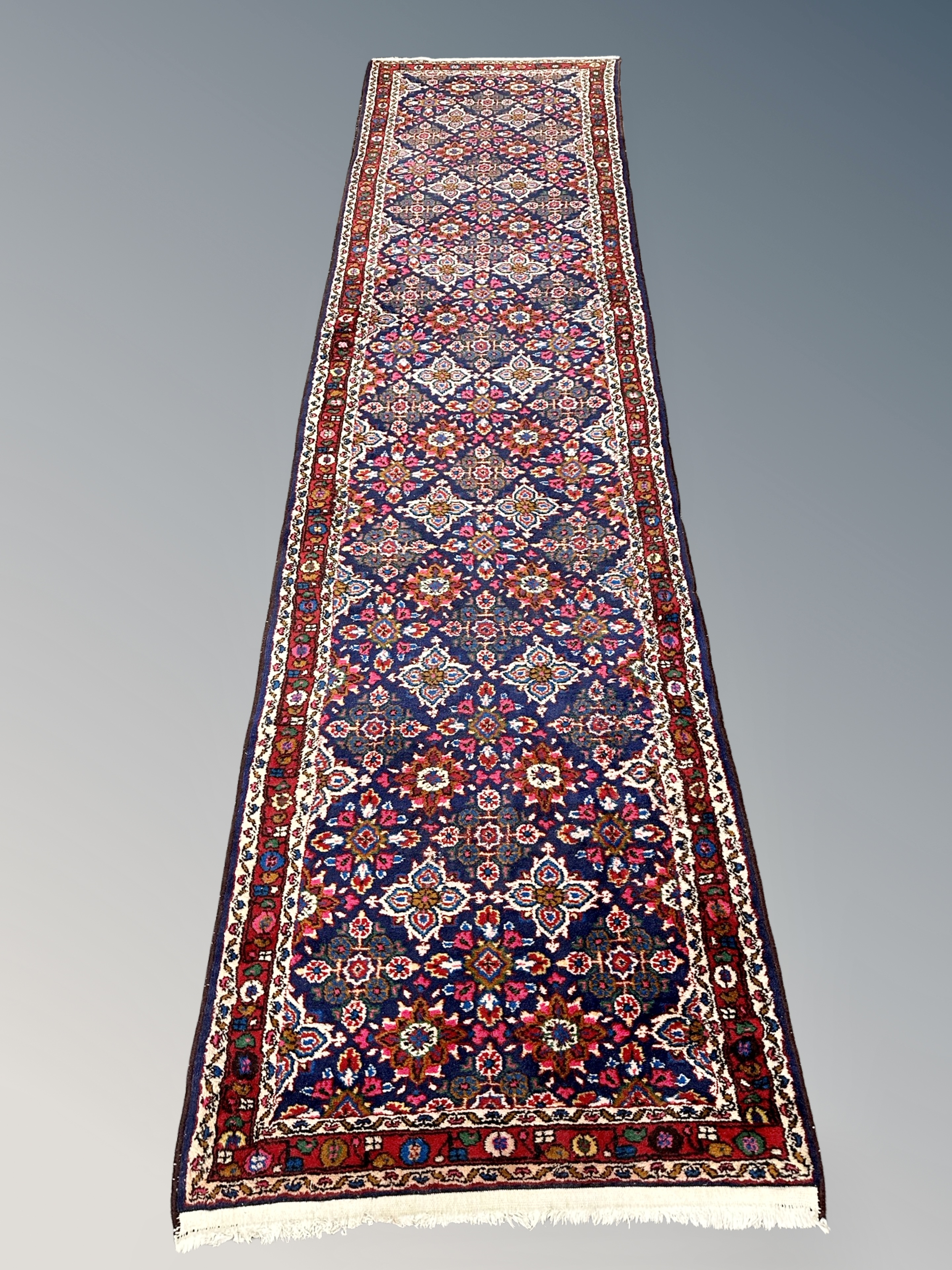A Feraghan runner, West Iran, with a dense floral lattice on an indigo field,