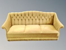 An early 20th century three seater settee in olive green tasseled and buttoned fabric,