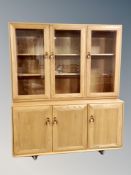 An Ercol elm Windsor three door sideboard with three glazed cabinets above,
