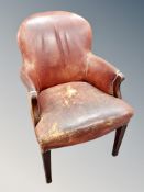 An early 20th century armchair upholstered in chestnut brown leather