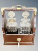 A reproduction brass mounted Tantalus with key and two crystal decanters height 32 cm