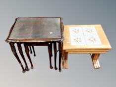 A reproduction mahogany nest of three tables and a further nest of three tiled tables