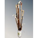 A ceramic stick pot containing assorted walking sticks including deer's hoof and antler handled