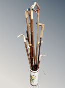 A ceramic stick pot containing assorted walking sticks including deer's hoof and antler handled