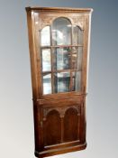 A carved oak glazed standing corner cabinet