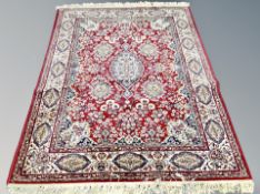 A machine made rug of Persian design on red ground,