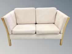 A Danish oak framed two seater settee in cream suede upholstery,
