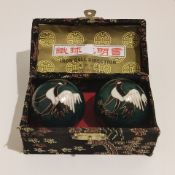 A pair of Chinese decorative iron balls in their original box.