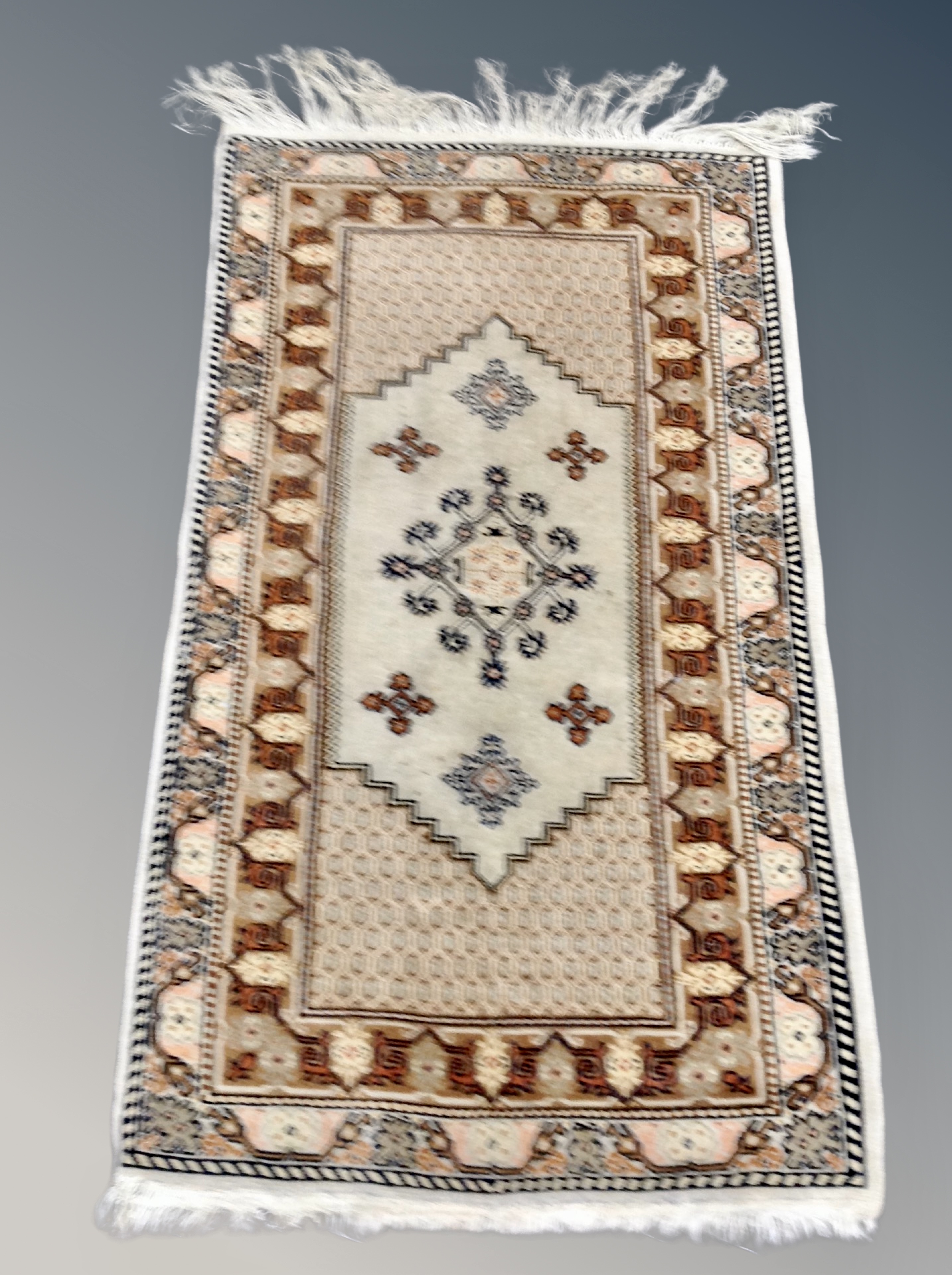An Anatolian fringed rug on beige ground 141 cm x 69 cm