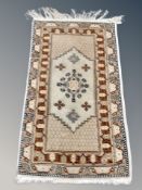 An Anatolian fringed rug on beige ground 141 cm x 69 cm