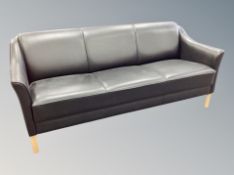 A Danish contemporary black leather four piece lounge suite comprising of three seater settee,