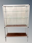 A glass and metal display cabinet with shelved interior and rosewood effect undershelf,