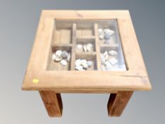 A contemporary pine display coffee table containing sea shells,