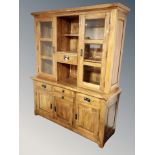 A contemporary oak dresser with glazed cupboards above,