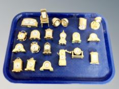 A tray of a collection of miniature brass novelty desk clocks