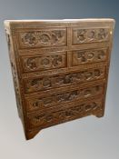 A Chinese heavily carved camphor wood seven drawer chest,
