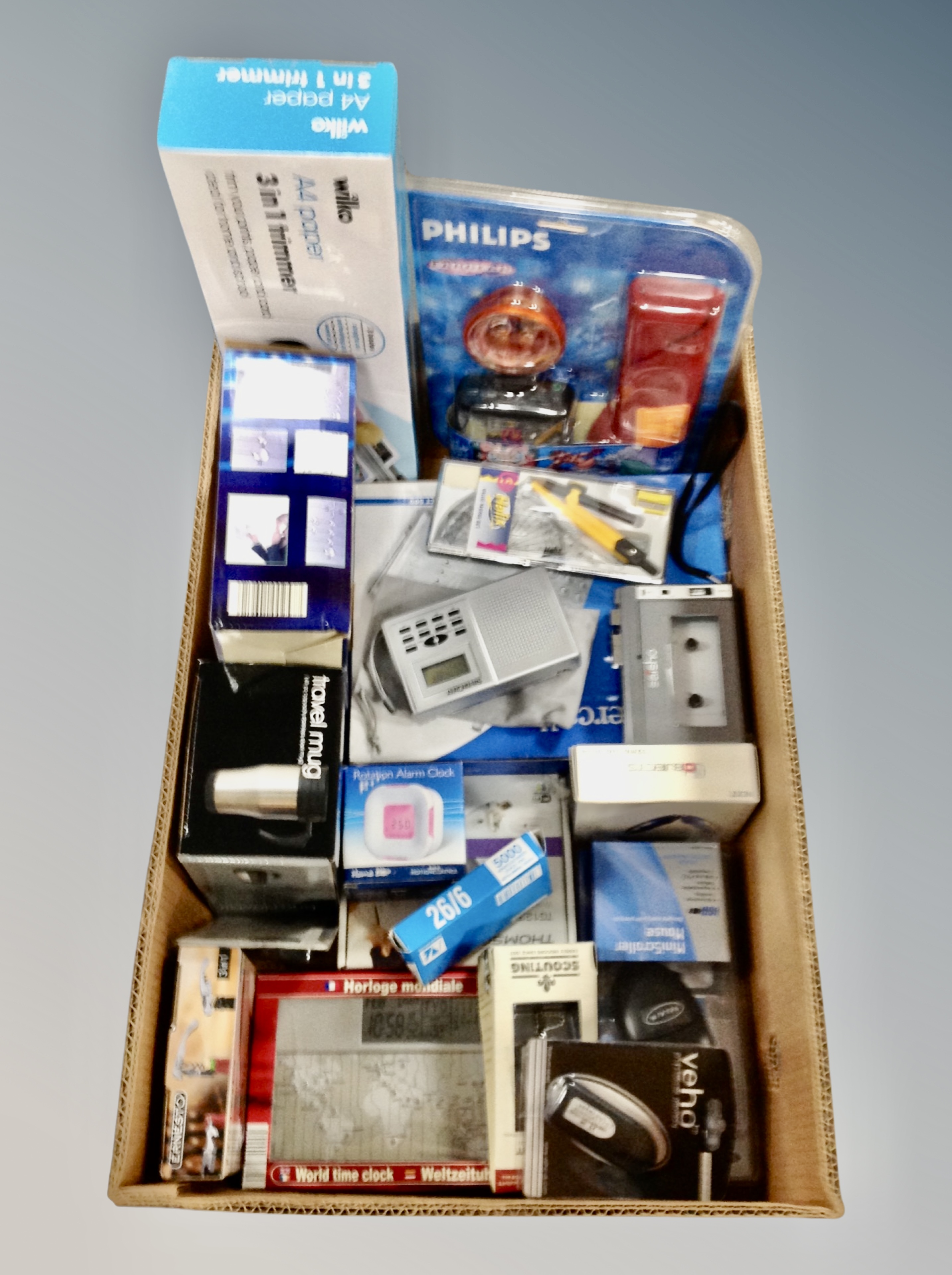 A box of travel mug, home phones, paper trimmers, wireless mouse, world clock, drawing instruments,