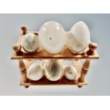 A pine egg rack and six marble and alabaster eggs