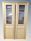 A pair of contemporary sentry door glazed bookcases with drawer beneath in an oak finish