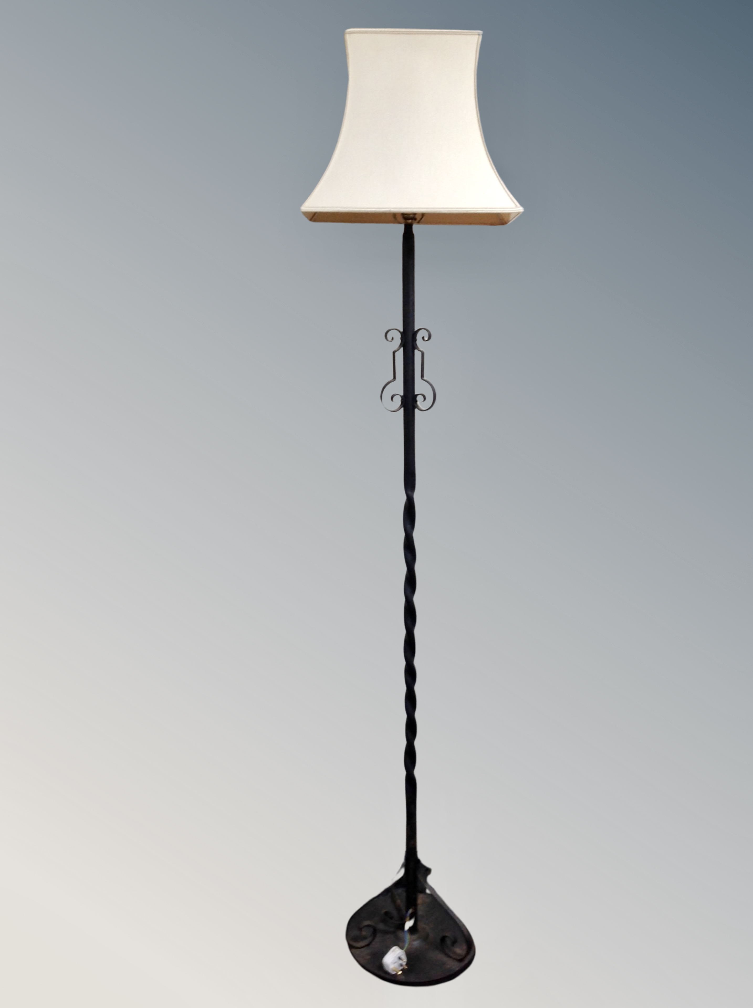 A wrought iron standard lamp with shade