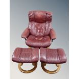 A Stressless swivel reclining armchair together with two stools in Burgundy leather