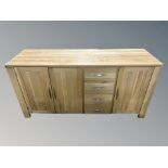 A contemporary oak triple door sideboard fitted with four drawers