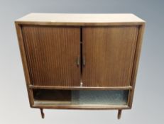 A mid century walnut veneered shutter door cabinet