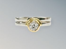 A platinum and yellow gold band ring set with a solitaire diamond weighing approximately 0.
