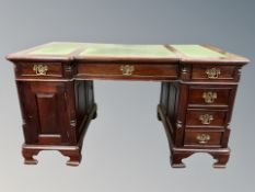 A reproduction mahogany twin pedestal writing desk fitted cupboard and drawers with three inset