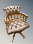 A Chesterfield swivel captain's chair upholstered in deep buttoned and studded brown leather