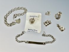 A silver identity bracelet, a padlock bracelet and several charms.