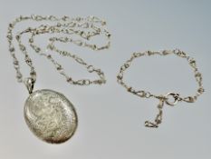 A large, engraved silver locket upon a fancy link silver chain, with matching bracelet.