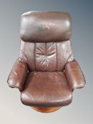 A Scandinavian swivel relaxer chair in brown leather upholstery