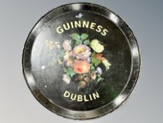 A circular papier mache tray bearing Guinness decoration,