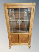 An Edwardian carved oak leaded glass door side cabinet,