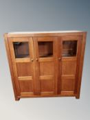 A contemporary stained pine triple door cabinet,
