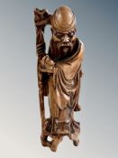 A Chinese carved root wood figure of an elder holding a staff,