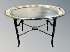 A Regency style papier mache mother of pearl inlaid and gilt oval tray on bamboo effect table with