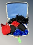 A vintage suitcase containing two bowler hats, fez, mask,