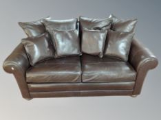 A contemporary brown leather two seater settee with scatter cushions,